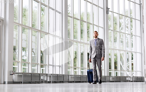 Image of businessman with travel bag walking along office
