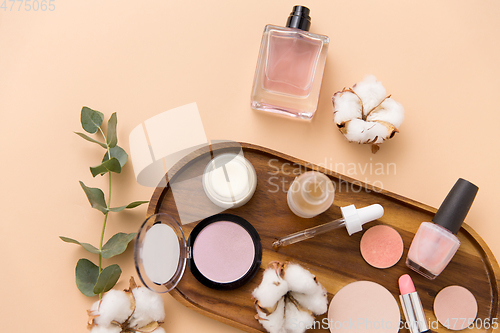 Image of makeup, perfume and cosmetics on wooden tray