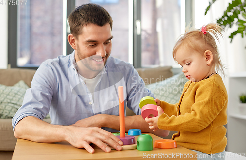 Image of father playing with little baby daughter at home