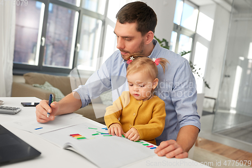 Image of working father with baby daughter at home office