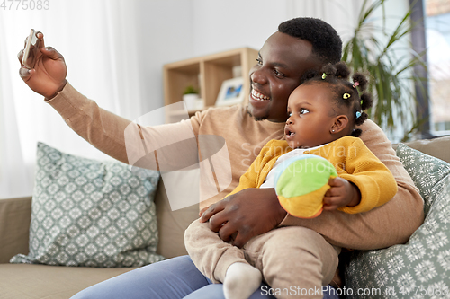 Image of happy father with baby taking selfie at home