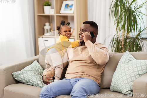 Image of father with baby at home calling on smartphone