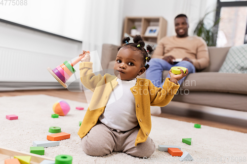 Image of african baby girl playing with toy blocks at home