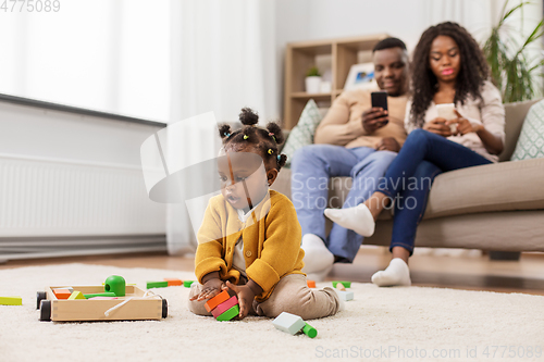 Image of african baby girl playing with toy blocks at home