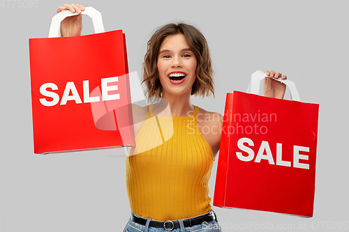 Image of happy young woman with shopping bags on sale