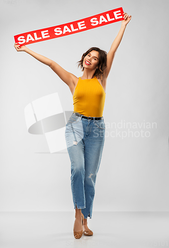 Image of happy smiling young woman posing with sale banner