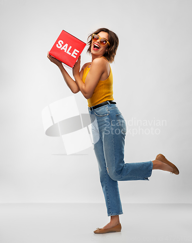 Image of happy smiling young woman posing with sale sign