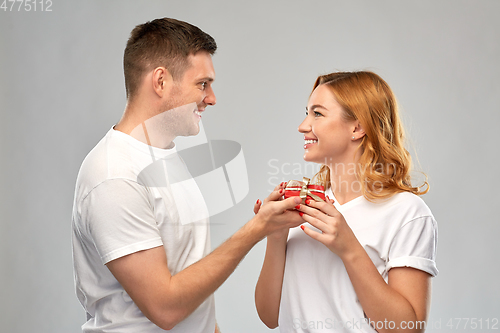 Image of happy couple in white t-shirts with christmas gift