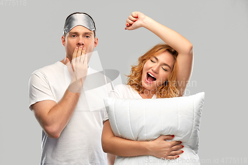 Image of yawning couple with eye sleeping mask and pillow