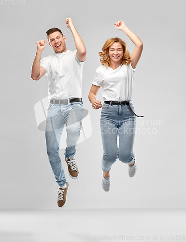 Image of happy couple in white t-shirts jumping