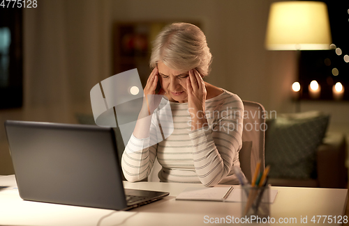 Image of tired senior woman with laptop at home at night