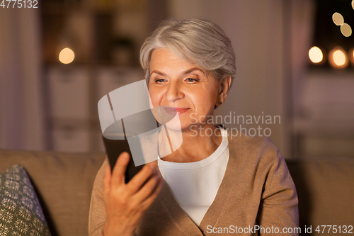 Image of happy senior woman with smartphone at home