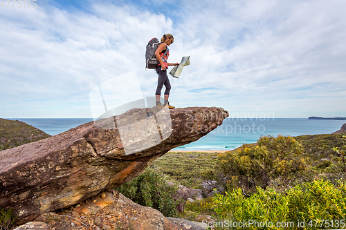 Image of Hiker on a rock precipice holding a map