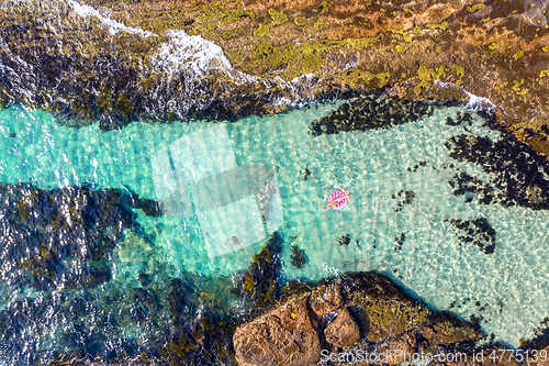 Image of Woman laying in a beautiful rock pool in a ring donut floaty