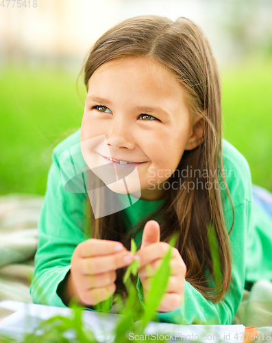 Image of Portrait of a little girl laying on green grass