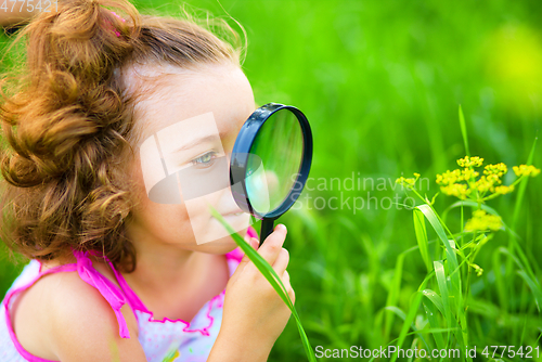 Image of Young girl is looking at flower through magnifier