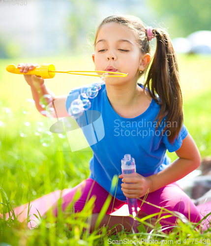 Image of Little girl is blowing a soap bubbles