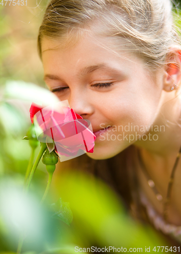 Image of Portrait of a cute little girl smelling rose