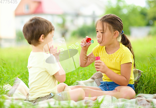 Image of Little girl and boy are blowing soap bubbles