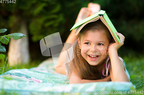 Image of Little girl is hiding under book outdoors