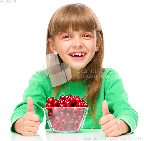 Image of Cute girl is eating cherries showing thumb up sigh