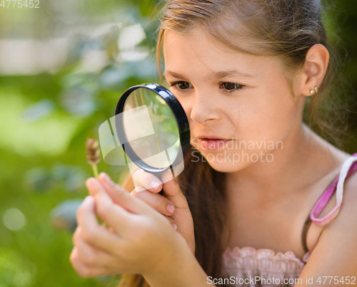 Image of Young girl is looking at flower through magnifier