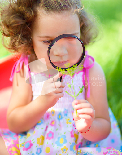 Image of Young girl is looking at flower through magnifier