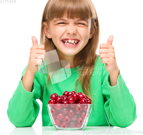 Image of Cute girl is eating cherries showing thumb up sigh