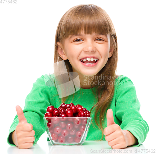 Image of Cute girl is eating cherries showing thumb up sigh