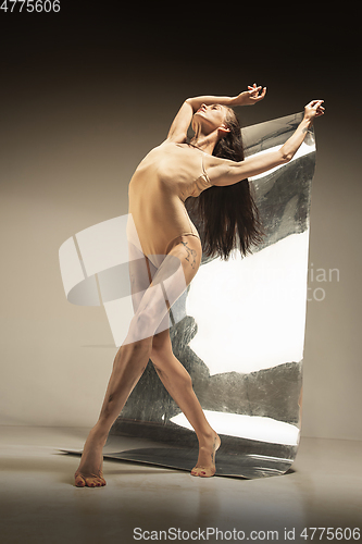 Image of Young and stylish modern ballet dancer on brown background