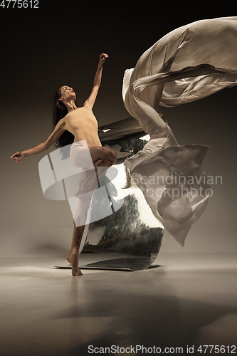 Image of Young and stylish modern ballet dancer on brown background