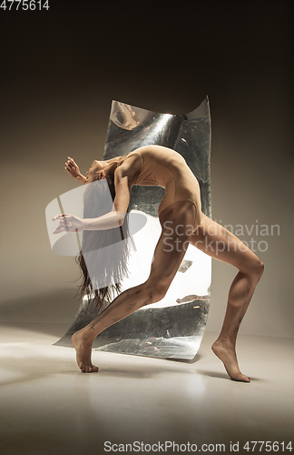 Image of Young and stylish modern ballet dancer on brown background