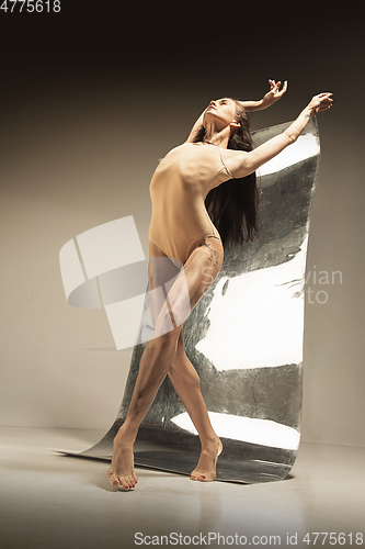 Image of Young and stylish modern ballet dancer on brown background