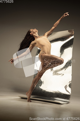 Image of Young and stylish modern ballet dancer on brown background