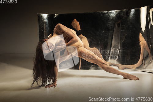 Image of Young and stylish modern ballet dancer on brown background