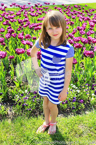 Image of young girl stands by lilac tulips