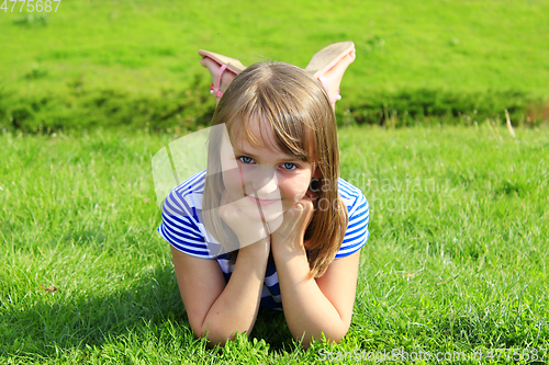 Image of portrait of little girl lying on the grass