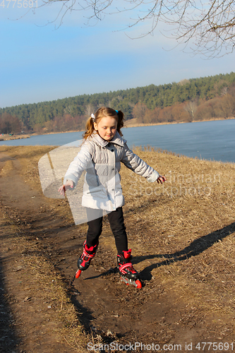 Image of young girl goes in roller skates on the ground