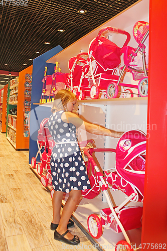 Image of Girl chooses a doll in a toy shop