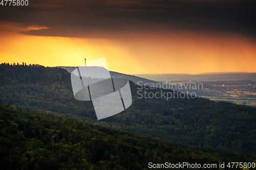 Image of dramatic stormy sky evening light over forest and radio tower