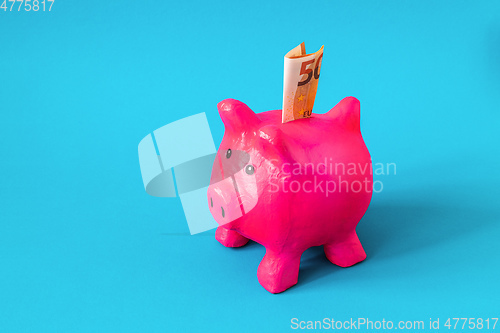 Image of pink papier mache piggy bank with 50 Euros