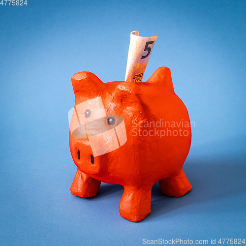 Image of red papier mache piggy bank with 5 Euros