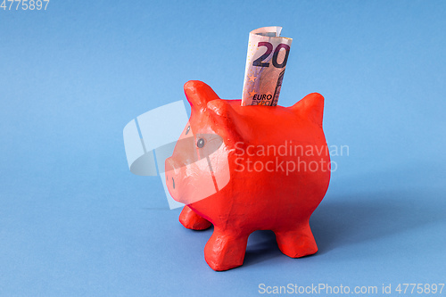 Image of red papier mache piggy bank with 20 Euros