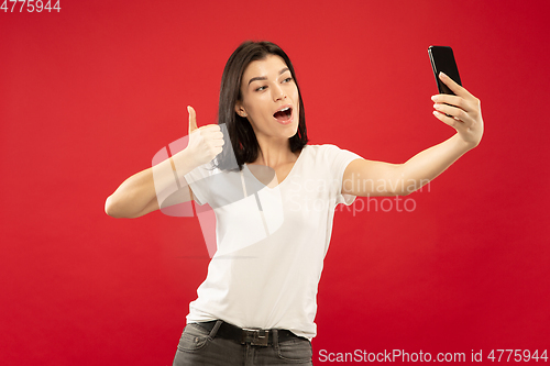 Image of Caucasian young woman\'s half-length portrait on red background