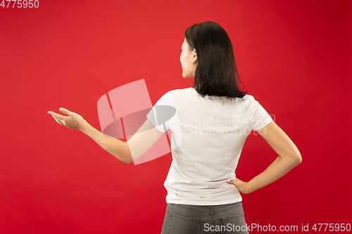 Image of Caucasian young woman\'s half-length portrait on red background