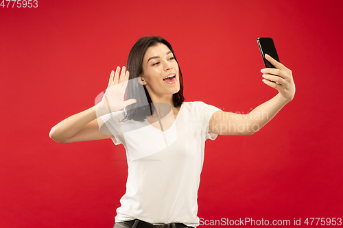 Image of Caucasian young woman\'s half-length portrait on red background