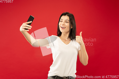 Image of Caucasian young woman\'s half-length portrait on red background