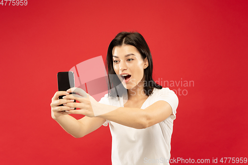 Image of Caucasian young woman\'s half-length portrait on red background