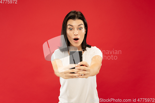 Image of Caucasian young woman\'s half-length portrait on red background