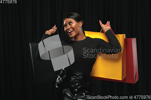 Image of Young woman in dress shopping on black background